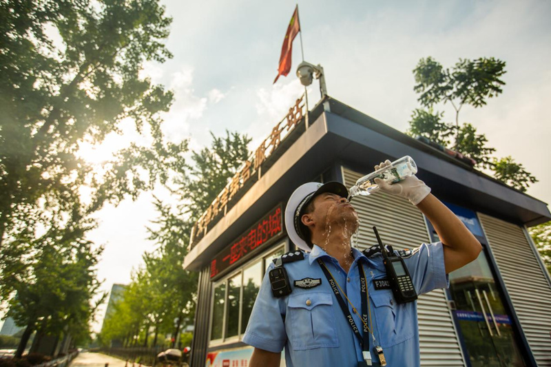 宜昌伍家交警衣衫被汗水浸透，在城東執(zhí)勤崗?fù)ぱa水防暑。陳華均攝