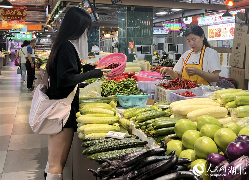 晚高峰時(shí)段，一年輕女子在洪山廣場(chǎng)地鐵站菜市場(chǎng)買菜。人民網(wǎng)記者 張雋攝