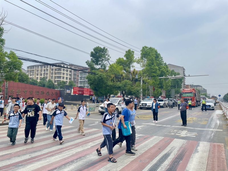 官塘驛中隊(duì)交警截停車流，形成安全屏障，守護(hù)小學(xué)生上放學(xué)路。